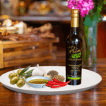 A 200ml bottle of Harissa Olive Oil on white plate with chili peppers, garlic, spices and sample olive oil