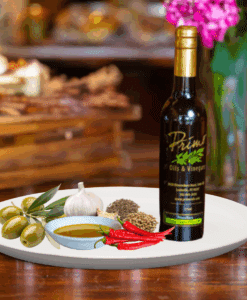 A 200ml bottle of Harissa Olive Oil on white plate with chili peppers, garlic, spices and sample olive oil