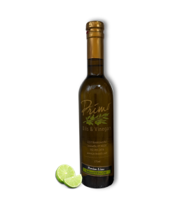 A 375ml bottle of Persian Lime Olive Oil with lime fruit.