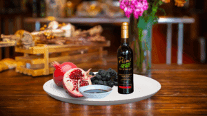 A 200ml bottle of Pomegranate Balsamic on white plate with pomegranate and sample balsamic vinegar