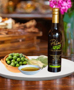 A 200 ml bottle of Biancolilla Olive Oil on white plate with olives from Italy, artichoke and sample olive oil