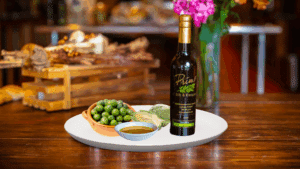 A 200 ml bottle of Biancolilla Olive Oil on white plate with olives from Italy, artichoke and sample olive oil