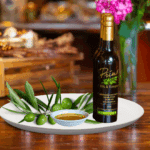 A 200ml bottle of Manzanillo Extra Virgin Olive Oil on white plate with green olives grown from Australia and sample olive oil
