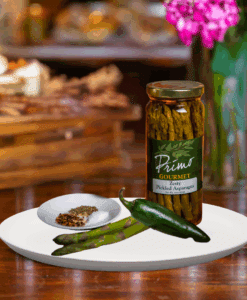 A jar of Zesty Pickled Asparagus on white plate with asparagus and green chili pepper