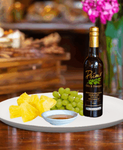 A 200ml bottle of Pineapple White Balsamic on white plate with pineapple slices and sample balsamic vinegar