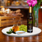 A 200ml bottle of Serrano Honey Vinegar on white plate with honey, green chili pepper and sample balsamic vinegar