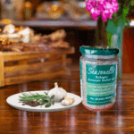 A jar of Seasonello Bologna Aromatic Herbal Salt with garlic, pepper and herbs on white plate