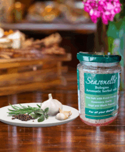 A jar of Seasonello Bologna Aromatic Herbal Salt with garlic, pepper and herbs on white plate