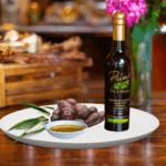 200ml bottle of Arbequina Olive Oil on white plate with olives grown in Chile and sample of olive oil