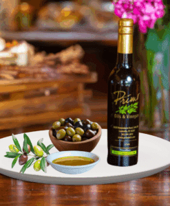 A 200ml bottle of Coratina EVOO on white plate with bowl of olives grown in Peru and sample olive oil