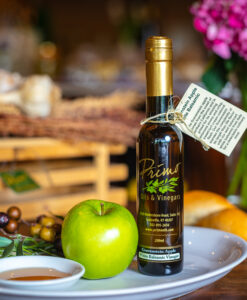 A 200 ml bottle of Gravenstein Apple White Balsamic on white plate with apple and sample balsamic vinegar