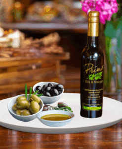 A 200ml bottle of Hojiblanca Extra Vigin Olive Oil on white plate with green and black olives on bowl and sample olive oil