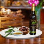 A 200ml bottle of Picual Extra Olive Oil on white plate with a bowl of purple olives from Chile and sample olive oil