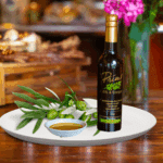 A 200ml bottle of Lentrisca Olive Oil on white plate with green olives grown in Portugal and sample olive oil
