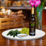 A 200ml bottle of Jalapeño White Balsamic Vinegar on white plate with green jalapeño peppers and sample balsamic vinegar