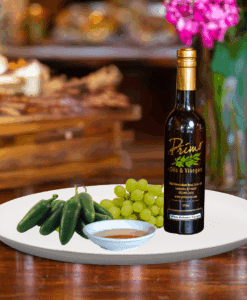 A 200ml bottle of Jalapeño White Balsamic Vinegar on white plate with green jalapeño peppers and sample balsamic vinegar