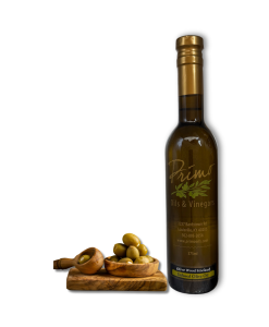 A 375ml bottle of Olive Wood Smoked Olive Oil with green olives on a wooden board.