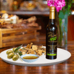 A 200ml bottle of Olive Wood Smoked Olive Oil on white plate with olive wood and sample olive oil