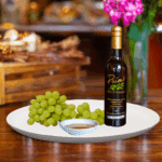 A 200ml bottle of Premium White Balsamic Vinegar Condimento on white plate with green grapes and sample balsamic vinegar