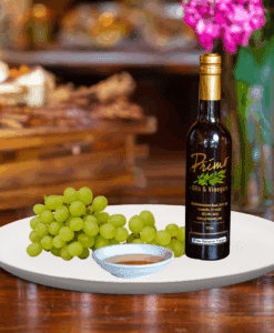 A 200ml bottle of Premium White Balsamic Vinegar Condimento on white plate with green grapes and sample balsamic vinegar