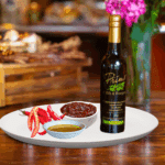 A 200ml bottle of Gochujang Evoo on white plate with spicy umami, red chili peppers and sample olive oil