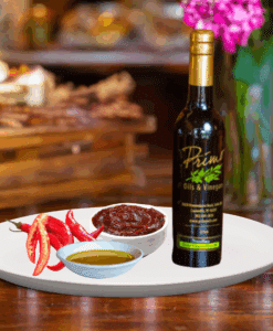 A 200ml bottle of Gochujang Evoo on white plate with spicy umami, red chili peppers and sample olive oil