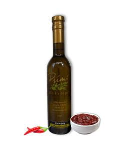 A 375ml bottle of Gochujang Olive Oil with bowl of spicy umami and red chili peppers.