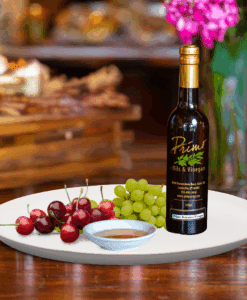 A 200ml bottle of Montmorency Cherry Rosé Balsamic Vinegar on white plate with cherries and sample balsamic vinegar