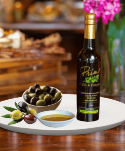 Bottle of Chetoui EVOO with Primo label and dish of olives next to it